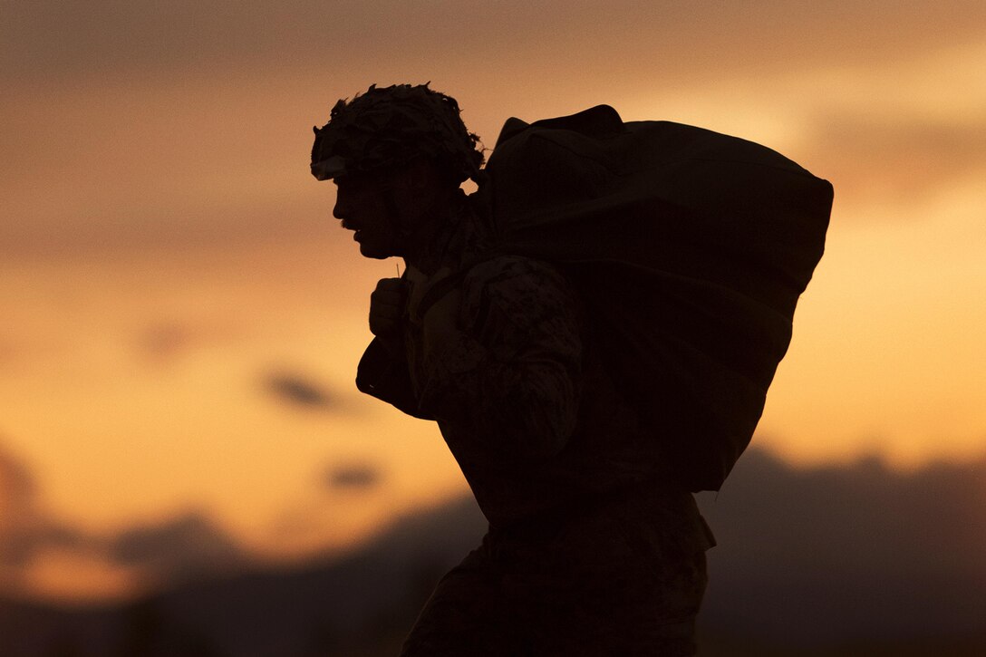 Marine Corps Cpl. Joshua Coulter carries his parachute from the drop zone to the rally point after jumping from an Air Force C-130 Hercules aircraft during Jump Week at Yokota Air Base, Japan, May 11, 2016. Coulter is assigned to the 3rd Reconnaissance Battalion, 3rd Marine Division, 3rd Marine Expeditionary Force. Air Force photo by Yasuo Osakabe
