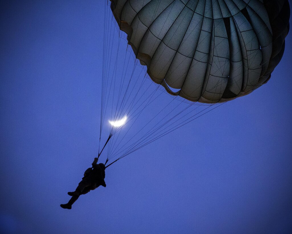 A Marine descends to the drop zone with the moon in the background after jumping from an Air Force C-130 Hercules aircraft during Jump Week at Yokota Air Base, Japan, May 11, 2016. Air Force photo by Yasuo Osakabe. 
