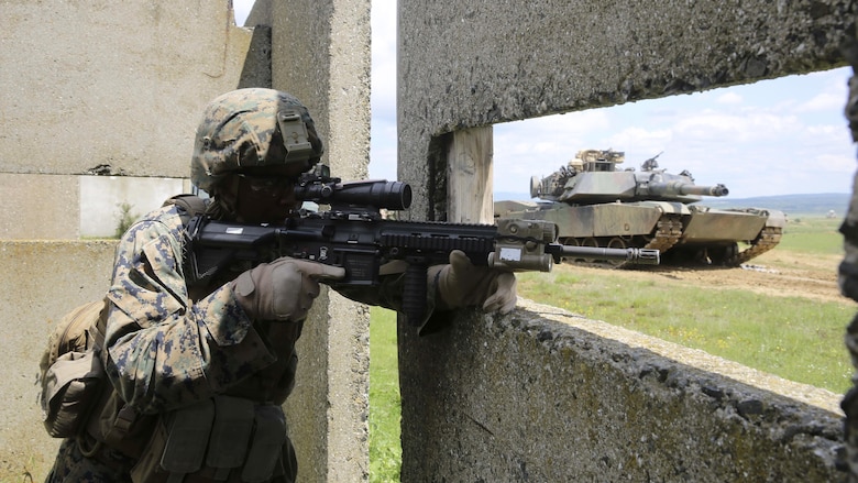 U.S. Marine Corps Lance Cpl. Jimmy Crumel III, a rifleman with Bravo Company, Special Purpose Marine Air-Ground Task Force Crisis Response-Africa, prepares to advance to the next building with support from an M1A1 Abrams tank for the assault on Military Operations on Urban Terrain Town during Platinum Lion 16-3 at the Novo Selo Training Area, Bulgaria, May 10, 2016. Hundreds of troops from five NATO countries came together to train with mechanized assets and demonstrate the ability to work seamlessly as one force. 