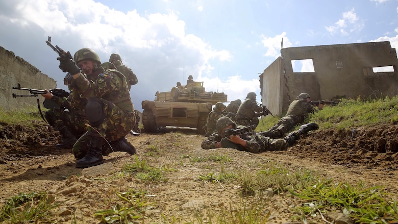Romanian soldiers with the 634th Infantry Battalion post rear security as a U.S. Marine Corps M1A1 Abrams tank clears the path ahead for the assault on Military Operations on Urban Terrain Town during Platinum Lion 16-3 at the Novo Selo Training Area, Bulgaria, May 10, 2016. Hundreds of troops from five NATO countries came together to train with mechanized assets and demonstrate the ability to work seamlessly as one force.