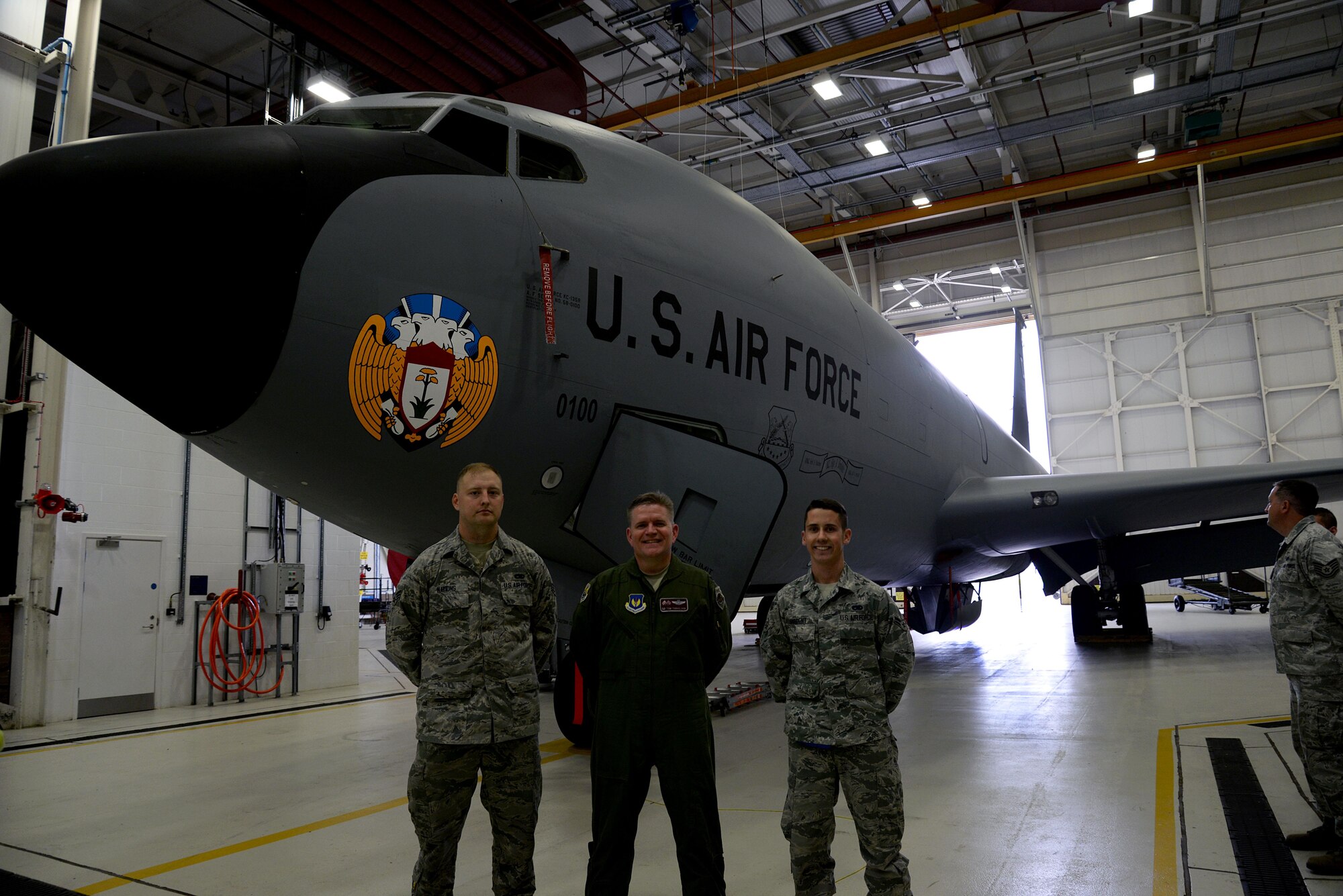 U.S. Air Force Senior Airman Shannon Nations, left, 100th Aircraft Maintenance Squadron jets specialist, and Airman 1st Class Logan Sargent, right, 100th AMXS crew chief, present the newly customized KC-135 Stratotanker to Col. Thomas D. Torkelson, 100th Air Refueling Wing commander, May 16, 2015, on RAF Mildenhall, England. The Stratotanker, with the tail number 0100, is assigned to be the new wing jet. (U.S. Air Force photo by Airman 1st Class Tenley Long/Released)