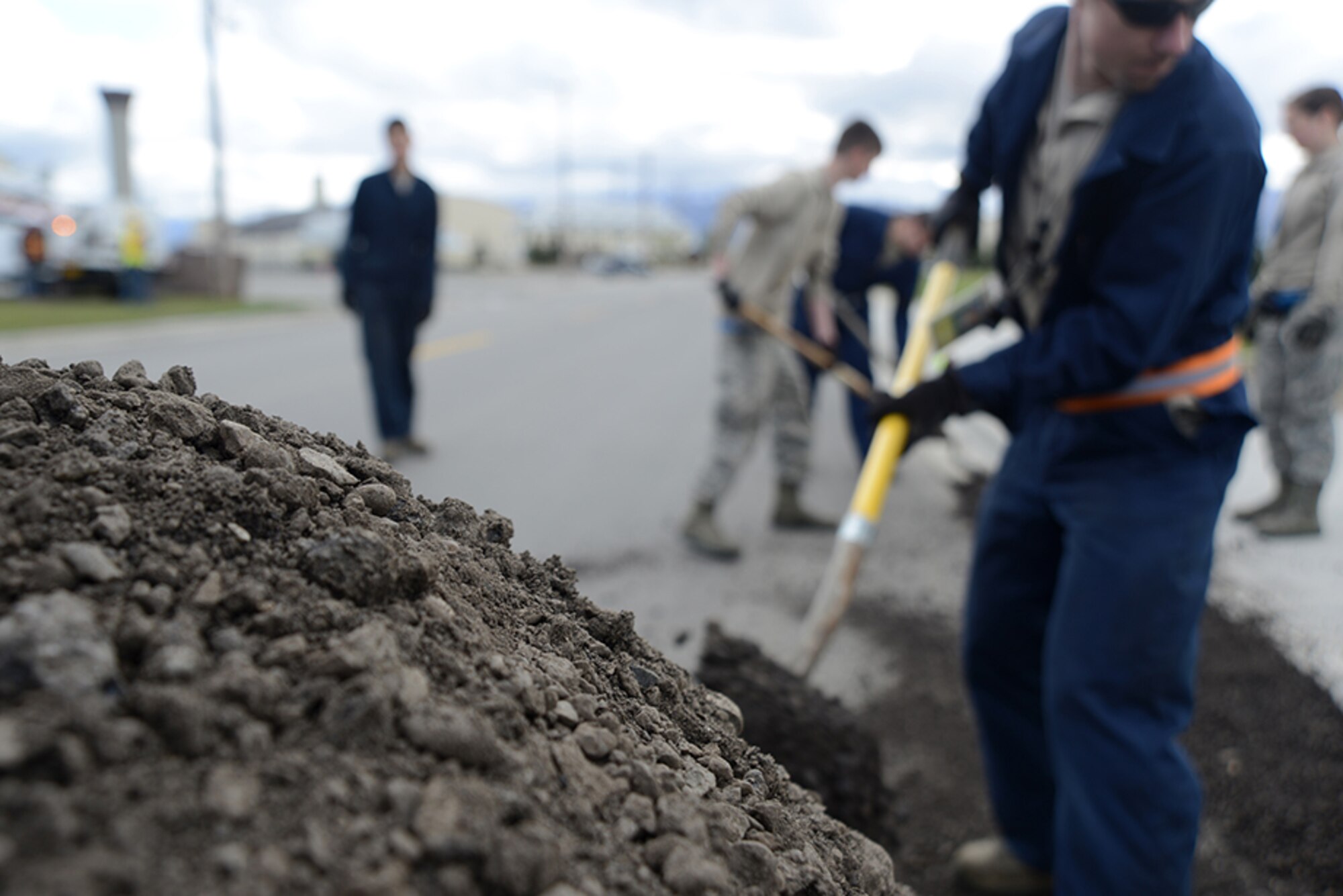 3rd Maintenance Squadron Airmen shovel gravel to create a makeshift ramp to ease the aircraft over a curb during the C-130 Hercules and F-102 Delta Dagger return to Heritage Park at Joint Base Elmendorf-Richardson, Alaska, May 7, 2016. The F-102 weighs more than 19,000 pounds and the C-130 weighs more than 75,000 pounds so the 3rd MXS implemented a few safety precautions. (U.S. Air Force photo by Airman 1st Class Christopher R. Morales)