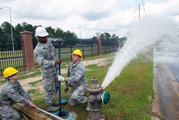 Water and fuels system maintenance specialists from the 23d Civil Engineer Squadron simulate repairing a damaged power line and fire hydrant after a car accident during a hurricane exercise, May 17, 2016, at Moody Air Force Base, Ga. After fixing the flooding from the hydrant, the 23d CES fire department was able to assess the injured driver. (U.S. Air Force photo by Airman 1st Class Greg Nash/Released)