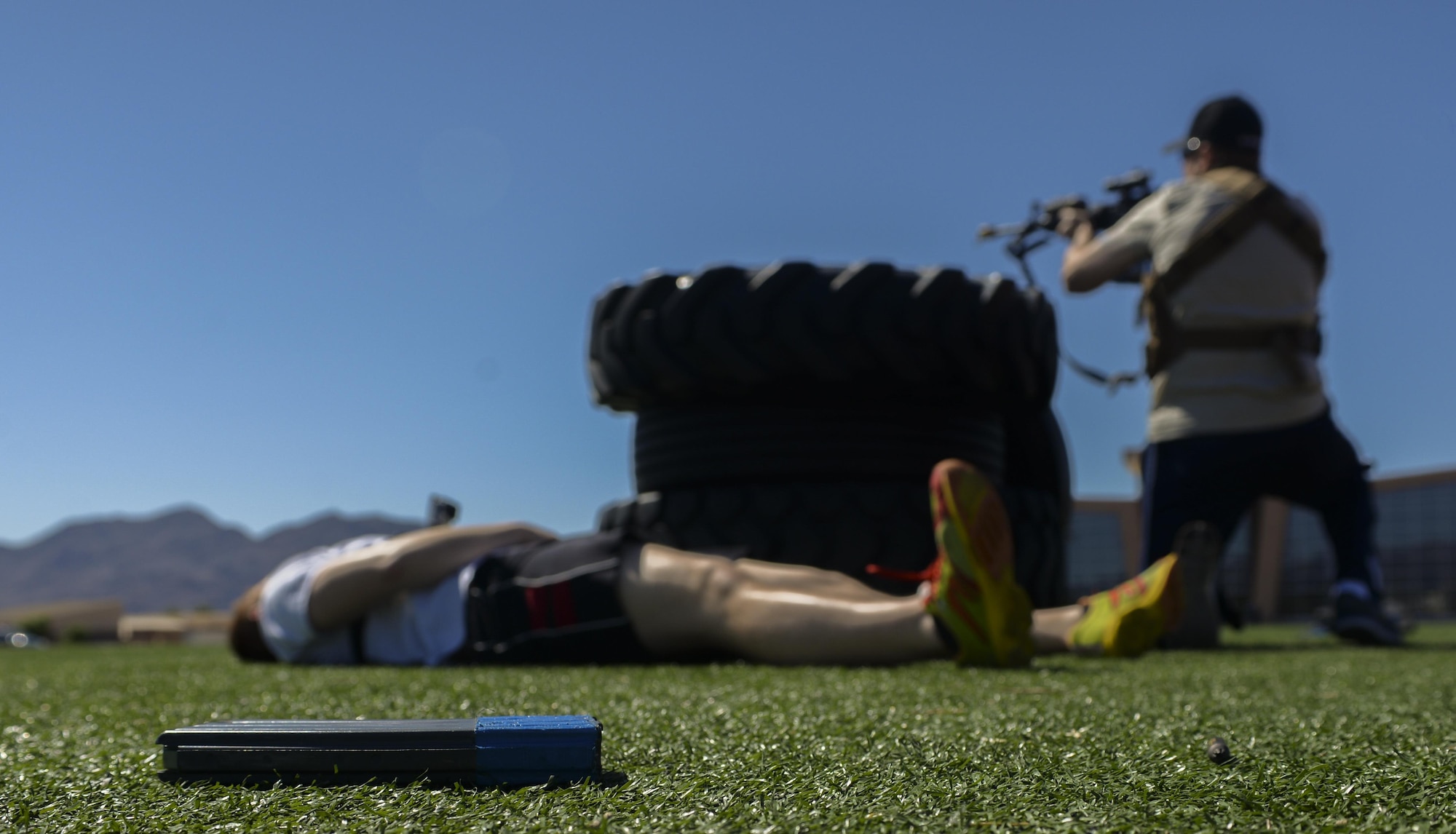 A used magazine lays on the field behind the Warrior Fitness Center as a simulated active shooter fires blanks at first responding 99th Security Forces Squadron Airmen during a base exercise at Nellis Air Force Base, Nev., May 12, 2016. There were over 300 participants from Nellis AFB, Creech AFB and Tenant Units. The participants included Wing Inspection Team (WIT) members, Scene Controllers for additional safety, and volunteers simulating victims and witnesses to the incident. (U.S. Air Force photo by Airman 1st Class Kevin Tanenbaum)