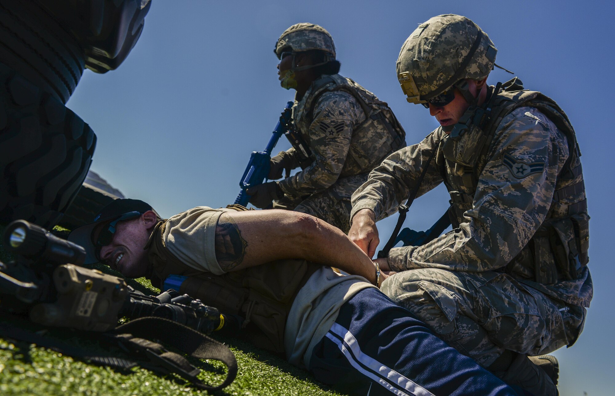 Airman 1st Class Robert Siegmann, 99th Security Forces Squadron, subdues and handcuffs a simulated active shooter during a base wide exercise at Nellis Air Force Base, Nev., May 12, 2016. These real world scenarios combined make this exercise one of the largest in the history of Nellis AFB. (U.S. Air Force photo by Airman 1st Class Kevin Tanenbaum)