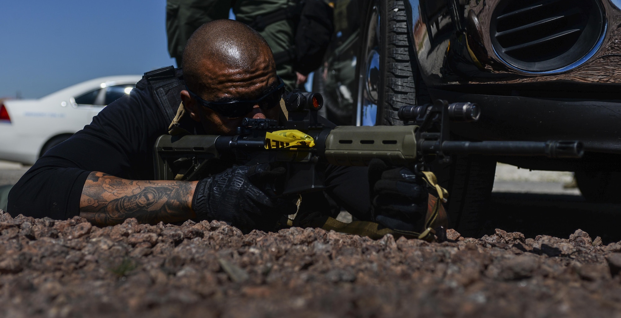 A Las Vegas Metropolitan Police Department officer lays prone as his team helps to secure the scene of a simulated active shooter during a base exercise at Nellis Air Force Base, Nev., May 12, 2016. In emergency situations such as an active shooter, local police and Security Forces work together in order to protect the base. (U.S. Air Force photo by Airman 1st Class Kevin Tanenbaum)
