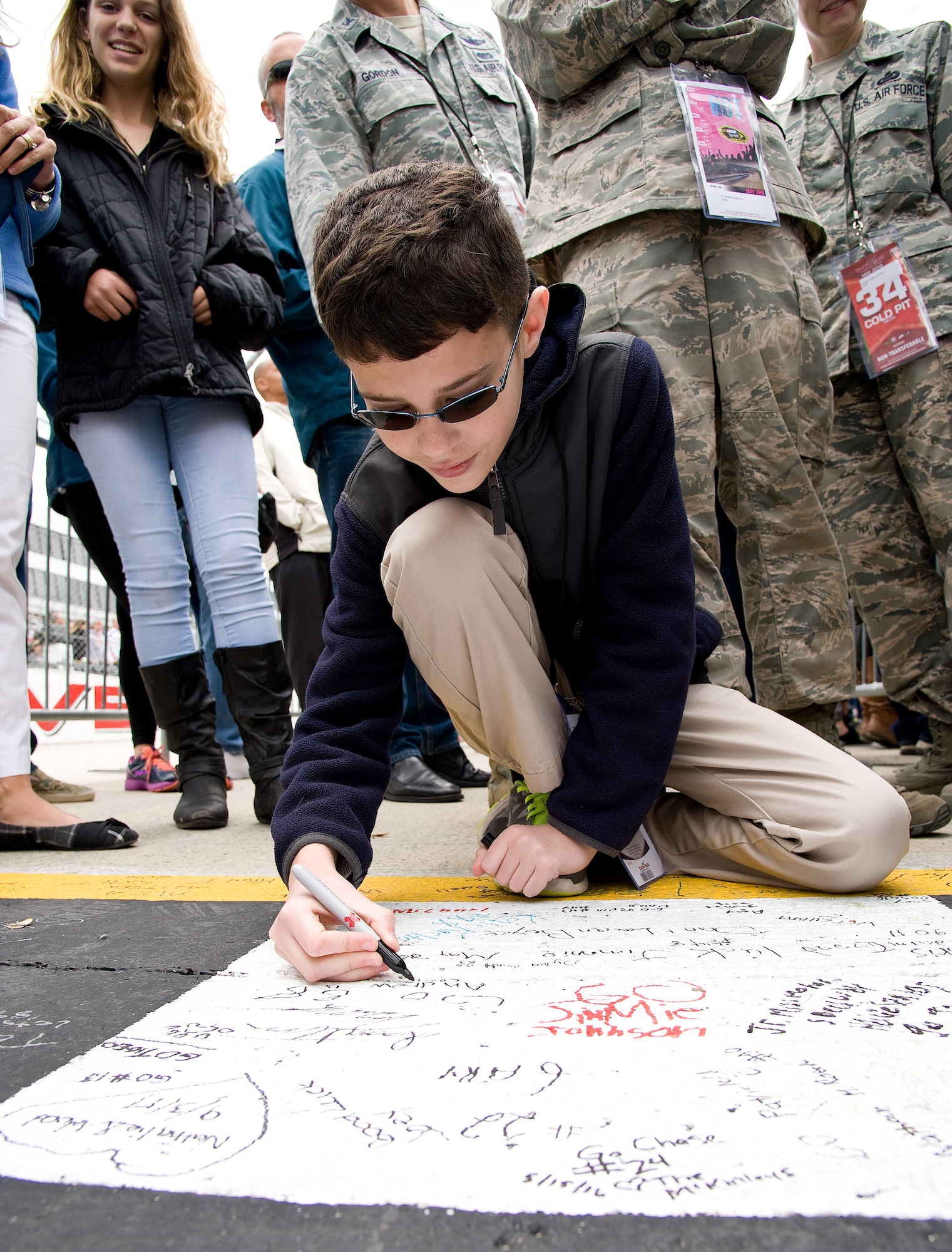 Andrew Gordon, son of Col. Kevin Gordon, 436th Airlift Wing vice commander, Dover Air Force Base, Del., writes on the racetrack start/finish line May 15, 2016, at Dover International Speedway, Dover, Del. Some race fans had the opportunity to write a message on the black and white-checkered line prior to the start of the AAA 400 Drive for Autism NASCAR Sprint Cup Series race. (U.S. Air Force photo/Roland Balik)