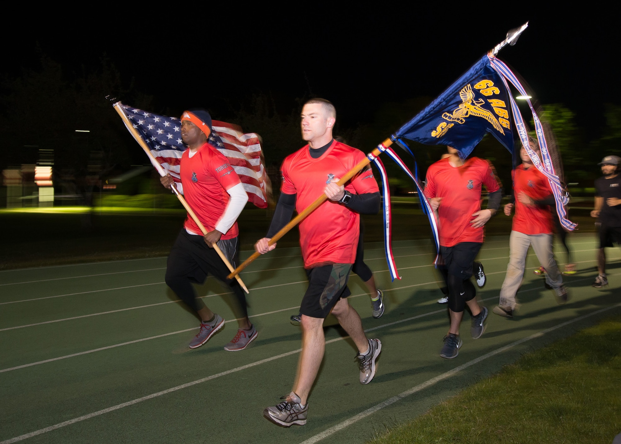 Capt. Christopher McNamee, right, and Tech. Sgt. Harvey Holloway, Jr., each members of the 66th Security Forces Squadron, lead Airmen while carrying the American flag and squadron guidon during a 24-Hour End of Watch Memorial Run at the base track May 16. To begin this year's Police Week activities, 66 SFS personnel hosted the memorial run in memory of Senior Airmen Kcey Ruiz and Nathan Sartain who died last fall while serving in Afghanistan. (U.S. Air Force photo by Mark Herlihy)