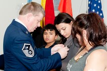 A U.S. Air Force Reserves Airman with the 71st Aerial Port Squadron pins an Air Force Achievement Medal on Sophia Gervasio, daughter of Tech. Sgt. Isaac Gervasio, during a memorial ceremony at Langley Air Force Base, Va., May 14, 2016. Following the ceremony, the 71st APS Airmen ran a mile in formation in honor of Gervasio and four other air transportation Airmen who lost their lives in 2015. (U.S. Air Force photo by Staff Sgt. R. Alex Durbin)