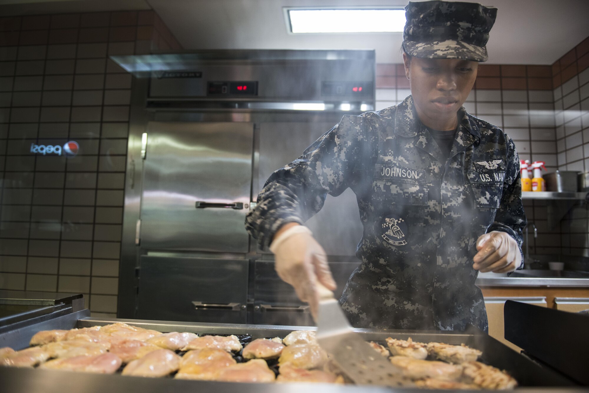 U.S. Navy Culinary Specialist Seaman Lareisha Johnson, assigned to Electronic Attack Squadron 132, Naval Air Station Whidbey Island, Wash., grills chicken prior to the lunch rush during RED FLAG-Alaska 16-1, May 11, 2016, in the Two Seasons Dining Facility, Eielson Air Force Base, Alaska. Servicemembers at the Two Seasons Dining Facility ensure the mission at Eielson is fueled with nutirents by preparing food around the clock. (U.S. Air Force photo by Staff Sgt. Ashley Nicole Taylor/Released)