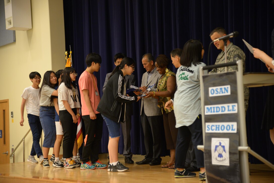 Osan American Middle School and Korean students receive certificates commemorating the completion of the Osan Good Neighbor English Camp during a ceremony May 18, 2016, in the OAMS at Osan Air Base, Republic of Korea. The English Camp paired Korean students with OMS families for three days to learn about American culture, shadow American students during class, and featured a tour of Osan AB for the students and their families. The English Camp program started in 2005 and has helped strengthen the community relationship between local Koreans and American service members and their families. (U.S. Air Force photo by Tech. Sgt. Travis Edwards/Released)