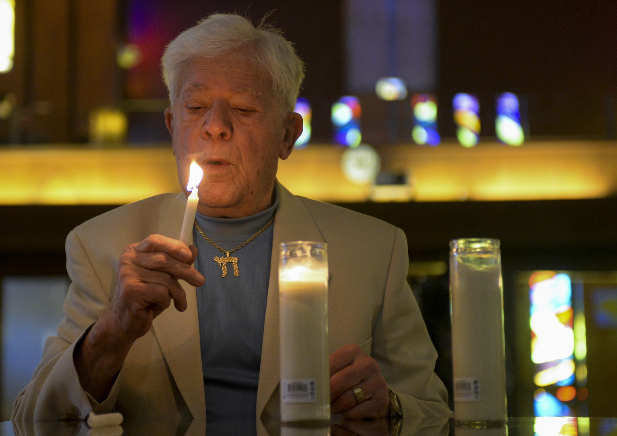 A Holocaust survivor blows out a flame after lighting a candle during the Holocaust Remembrance Commemoration and Candle Lighting Ceremony at Nellis Air Force Base, Nev., May 9, 2016. The Holocaust Remembrance Week consisted of a 5k awareness run, candle lighting ceremony, and luncheon. (U.S. Air Force photo by Airman 1st Class Kevin Tanenbaum)