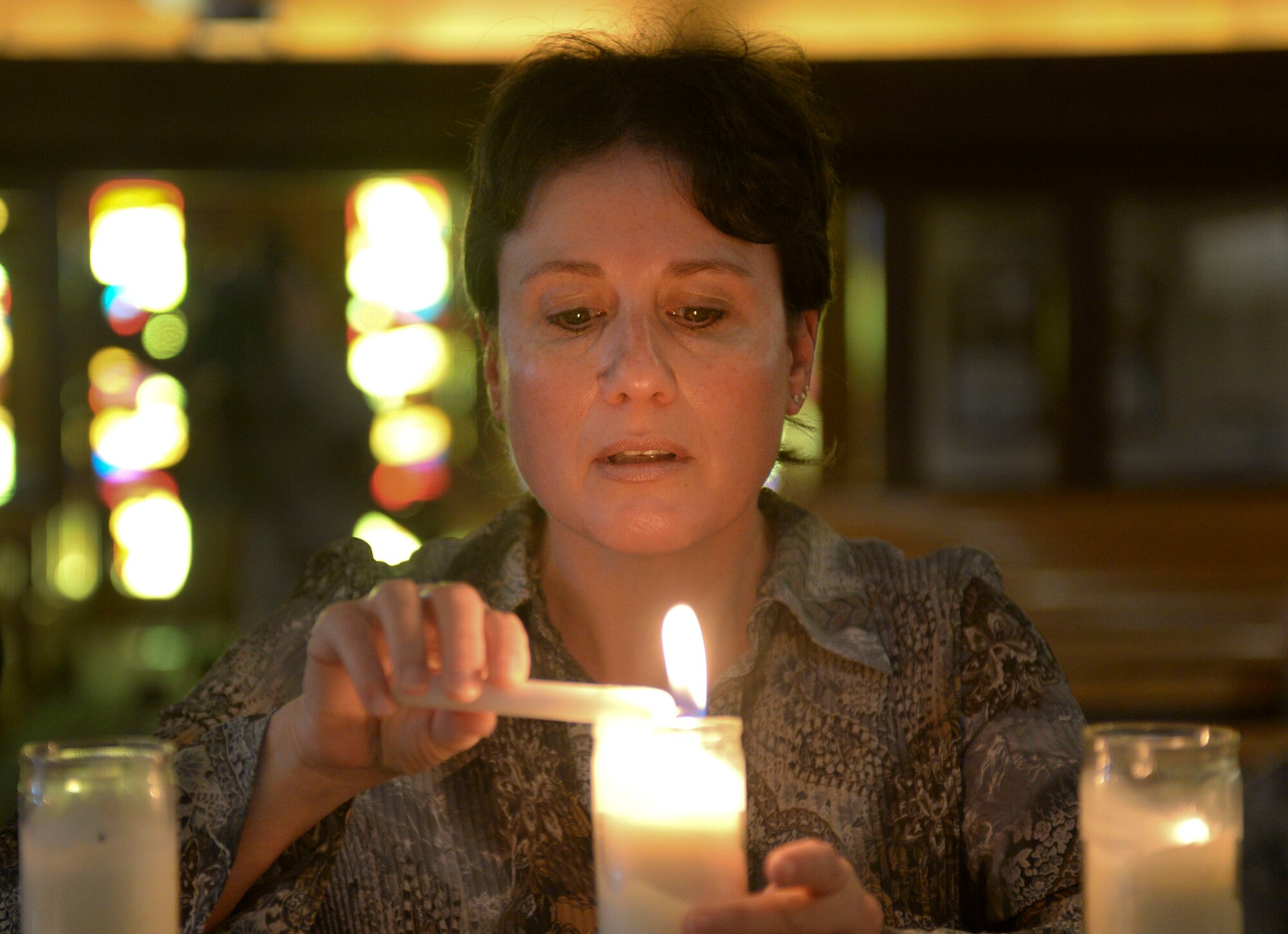 A Holocaust survivor lights a candle during the Holocaust Remembrance Commemoration and Candle Lighting Ceremony at Nellis Air Force Base, Nev., May 9, 2016. The survivors that attended were present to share their stories with the Airmen of Nellis AFB. (U.S. Air Force photo by Airman 1st Class Kevin Tanenbaum)