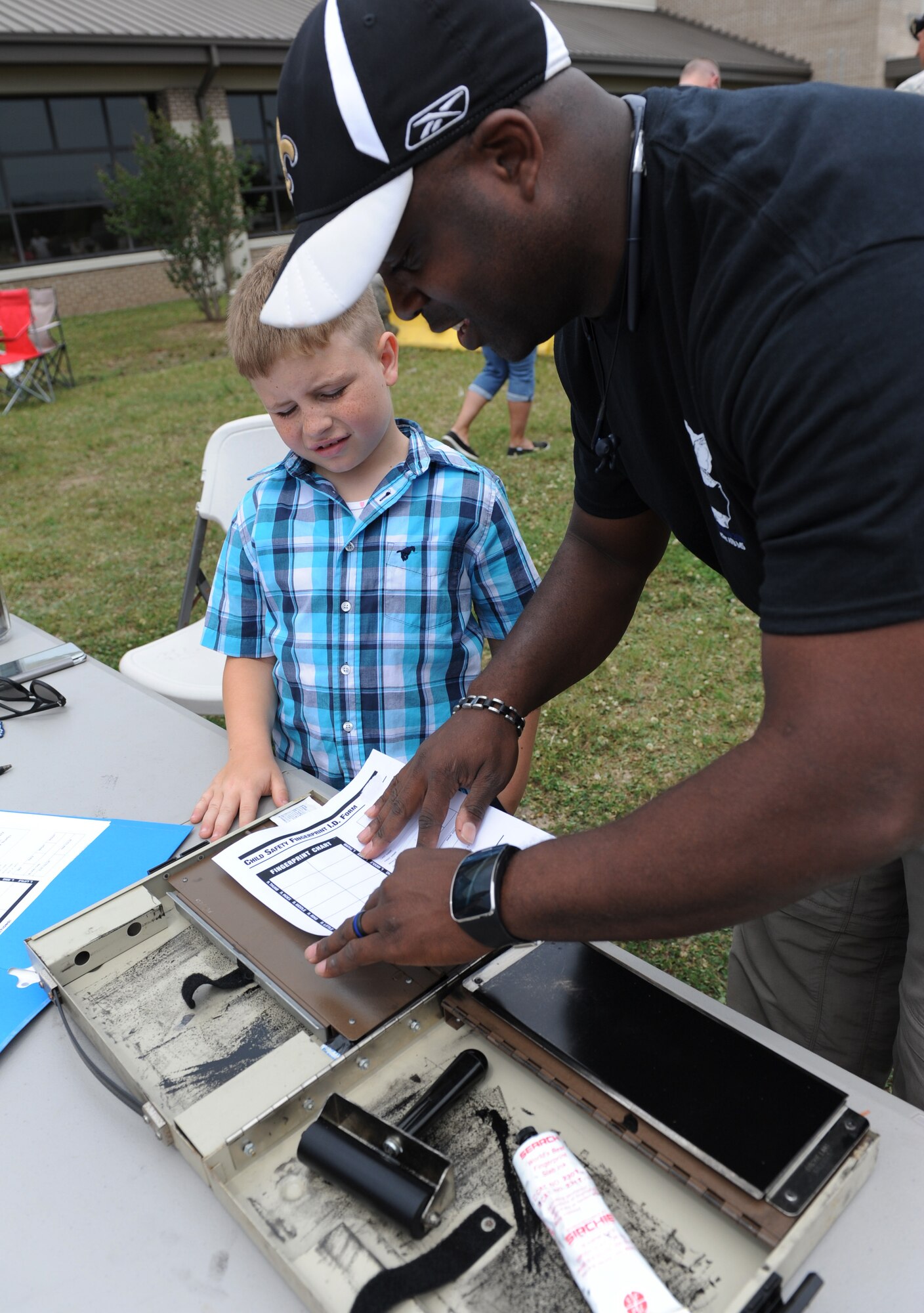 Eric Dalsin II, son of Marcy Dalsin, has his finger prints taken by Tech. Sgt. Jason Gavin, 81st Security Forces Squadron investigator, during the 81st SFS Fun Day at the base exchange May 16, 2016, Keesler Air Force Base, Miss. The event was held during National Police Week, which recognizes the service of law enforcement men and women who put their lives at risk every day. (U.S. Air Force photo by Kemberly Groue)