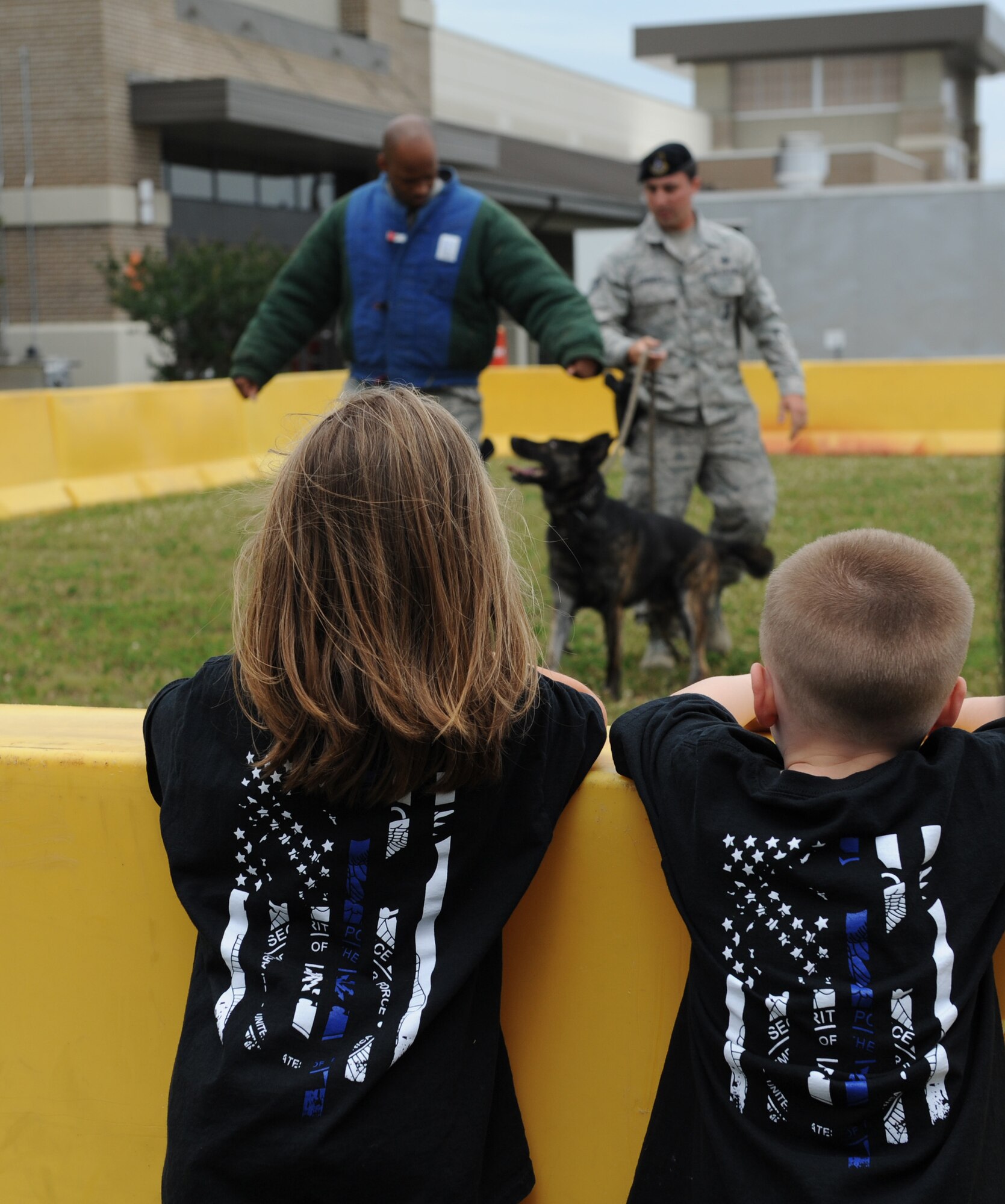 LJ McCormick, daughter of Staff Sgt. Kelli McCormick, 81st Security Forces Squadron police services NCO in charge, and Jaxsen Sproston, son of Maj. Devin Sproston, 81st SFS commander, watch a military working dog demo during the 81st SFS Fun Day at the base exchange May 16, 2016, Keesler Air Force Base, Miss. The event was held during National Police Week, which recognizes the service of law enforcement men and women who put their lives at risk every day. (U.S. Air Force photo by Kemberly Groue)