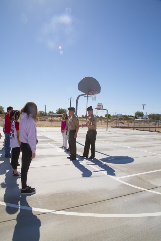 Cpl. Robert Taylor, communications specialist aboard Marine Corps Logistics Base Barstow, and Cpl. Brandon Dacier, assistant counselor, teach students from the Yermo School in Yermo, Calif., the proper position of attention during a Drill and Ceremonies training session, May 12, 2016. The corporals and various other Barstow Marines spent the afternoon teaching the Yermo students the basics of marching, saluting, and military bearing during their Civil War Days event.