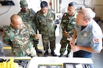 Suriname Army Capt. Henri Kasanradji, logistics officer, left, discusses equipment used by Lt. Billy Potter, firefighter with the Rapid City Fire Department, during hazardous material spill response, as Army Capt. Ulrich Morgan, Air Force Capt. Radjindrekoemar Soemai and Army Capt. Joeri Kasandiredjo, all members of the Suriname Defense Force, look on during a subject matter expert exchange in Rapid City, S.D., May 15, 2016. The exchange focused on the handling, containment and disposing of hazardous materials and conducted as a part of the Suriname-South Dakota State Partnership Program. 