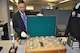 Yancy Mailes, Command Historian, shows off a chest containing “bomb com” cups awarded to various Strategic Air Command wings for their annual competition. Several of the cups are displayed in front of the chest. The new Global Strike Research Facility will house these artifacts as well as command archives for both SAC and AFGSC. Staff will have the ability to check out several of these lineage items for command events (Air Force Photo by TSgt. Ave Young, Air Force Global Strike Command Public Affairs).