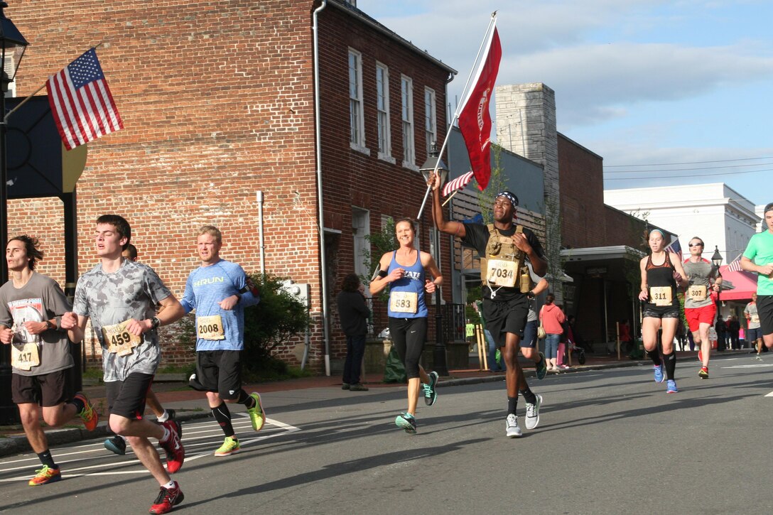 Jesse Thornton, 20 (wearing 7034), of Washington, D.C., carries a Marine Corps flag as he runs in the ninth annual Marine Corps Historic Half marathon May 15 through downtown Fredericksburg.