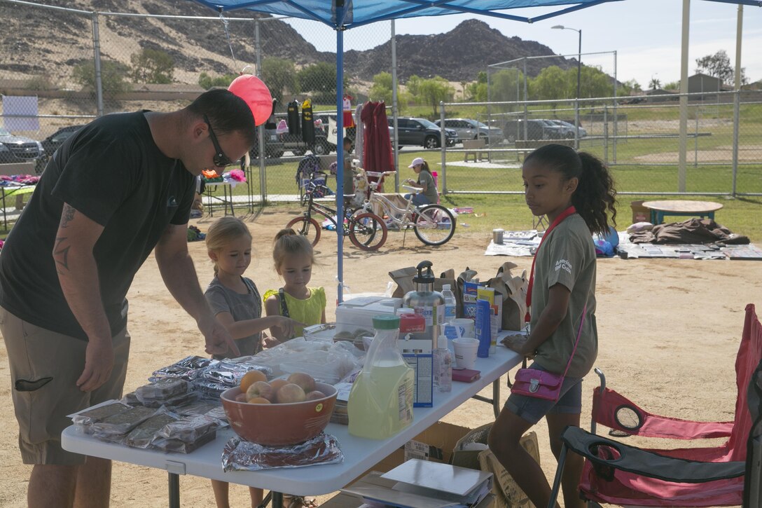 Dyani Felicianes, member, American Red Cross Youth Club, sells baked treats to Combat Center patrons at the Lincoln Military Housing athletic field May 7, 2016. The club, run by student members, holds charity events to show members the importance of giving back to the community. Fifty-five percent of the proceeds from each event go toward charity and the remaining is donated to the American Red Cross.  (Official Marine Corps photo by Cpl. Thomas Mudd/Released)