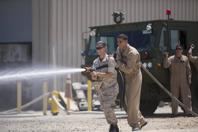 Lance Cpl. Jacob Martin, aircraft rescue and firefighting specialist, Marine Wing Support Squadron 374,  helps his wife Gabriella operate a fire hose at the Strategic Expeditionary Landing Field during the squadron’s Jane Wayne Day April 29, 2016. (Official Marine Corps photo by Cpl. Julio McGraw/Released)