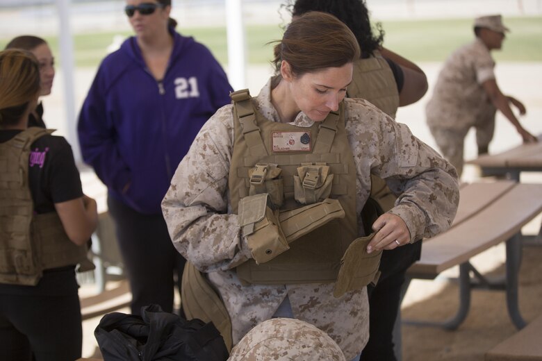 Jennifer Harlacher, wife of Staff Sgt. Matthew Harlacher, motor transportation chief, Marine Wing Support Squadron 374, adjusts her husband’s plate carrier at Del Valle Field during the squadron’s Jane Wayne Day April 29, 2016. (Official Marine Corps photo by Cpl. Julio McGraw/Released)
