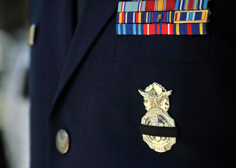 An Airman from the 319th Security Forces Squadron wears a mourning band on his badge during the National Police Week Memorial Service at Grand Forks County Court House May 17, 2016, in Grand Forks, N.D. The mourning band is symbolic in law enforcement and is worn upon the line of duty death of an active law enforcement officer in a department. (U.S. Air Force photo/Senior Airman Xavier Navarro)