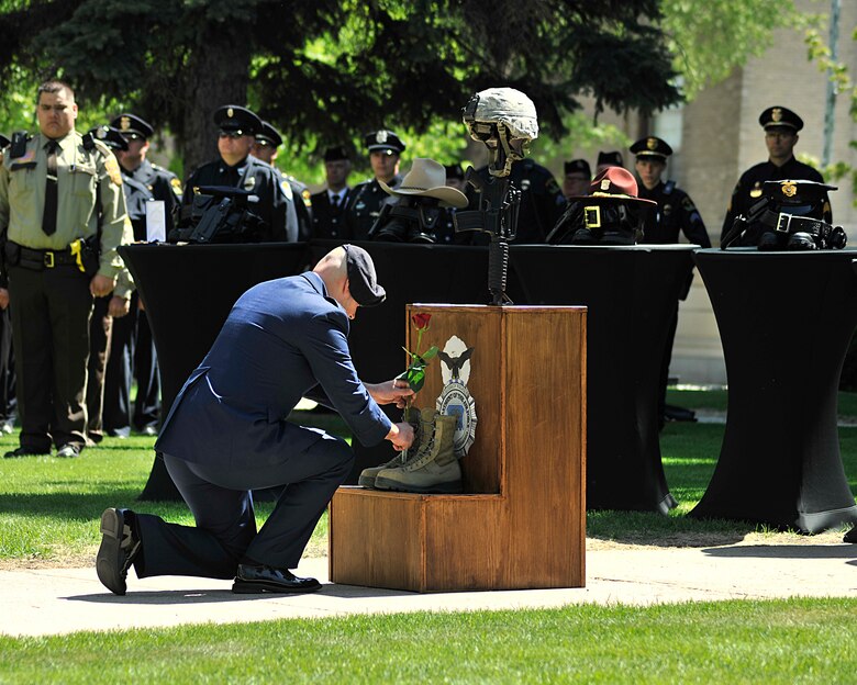 Capt. Kendall Benton, 319th Security Forces Squadron operations officer, sets a rose on a fallen warrior memorial during the National Police Week Memorial Service at Grand Forks County Court House May 17, 2016, in Grand Forks, N.D.  The 319th Security Forces Squadron was one of the agencies that participated in the event. (U.S. Air Force photo/Senior Airman Xavier Navarro)