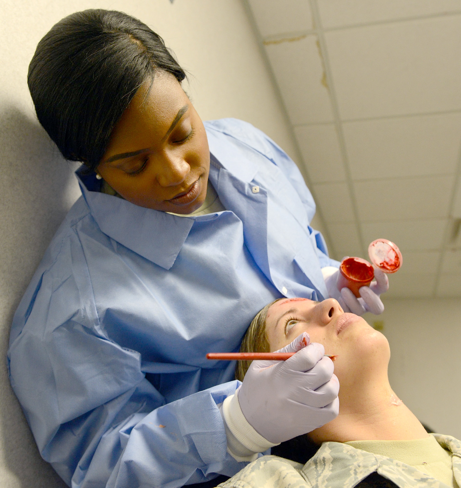 Senior Airman Brittinauna Wilson, 78th Medical Support Squadron laboratory technician, uses makeup and skill to simulate injuries on Senior Airman Shawnee Ryan, also a 78th Medical Support Squadron laboratory technician.(U.S. Air Force photo by Tommie Horton)