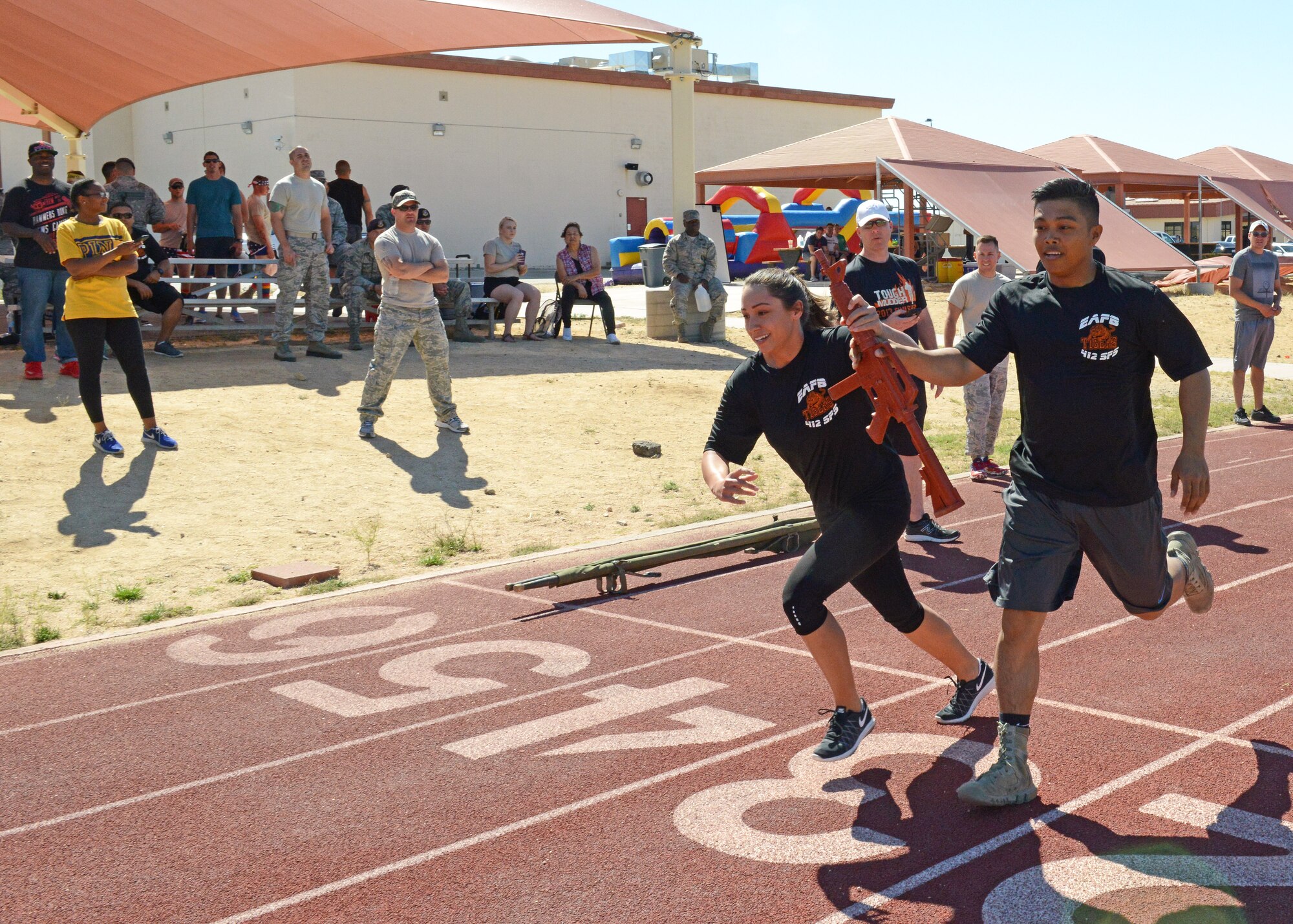 Staff Sgt. Nastasha Guerrero, 412th Security Forces Squadron, takes off running after receiving a dummy rifle from fellow defender Senior Airman Renz Delacruz during a relay race at the Defender Olympics May 19. (U.S. Air Force photo by Kenji Thuloweit) 