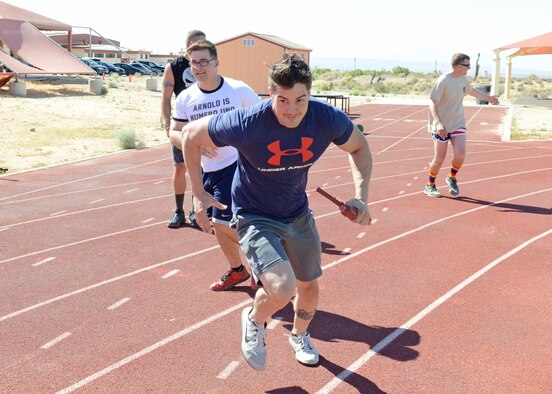 Senior Airman Anthony Hanneman, 412th Security Forces Squadron, grabs the dummy rifle from a teammate and takes off for a lap around the track during a relay race May 19. (U.S. Air Force photo by Kenji Thuloweit) 