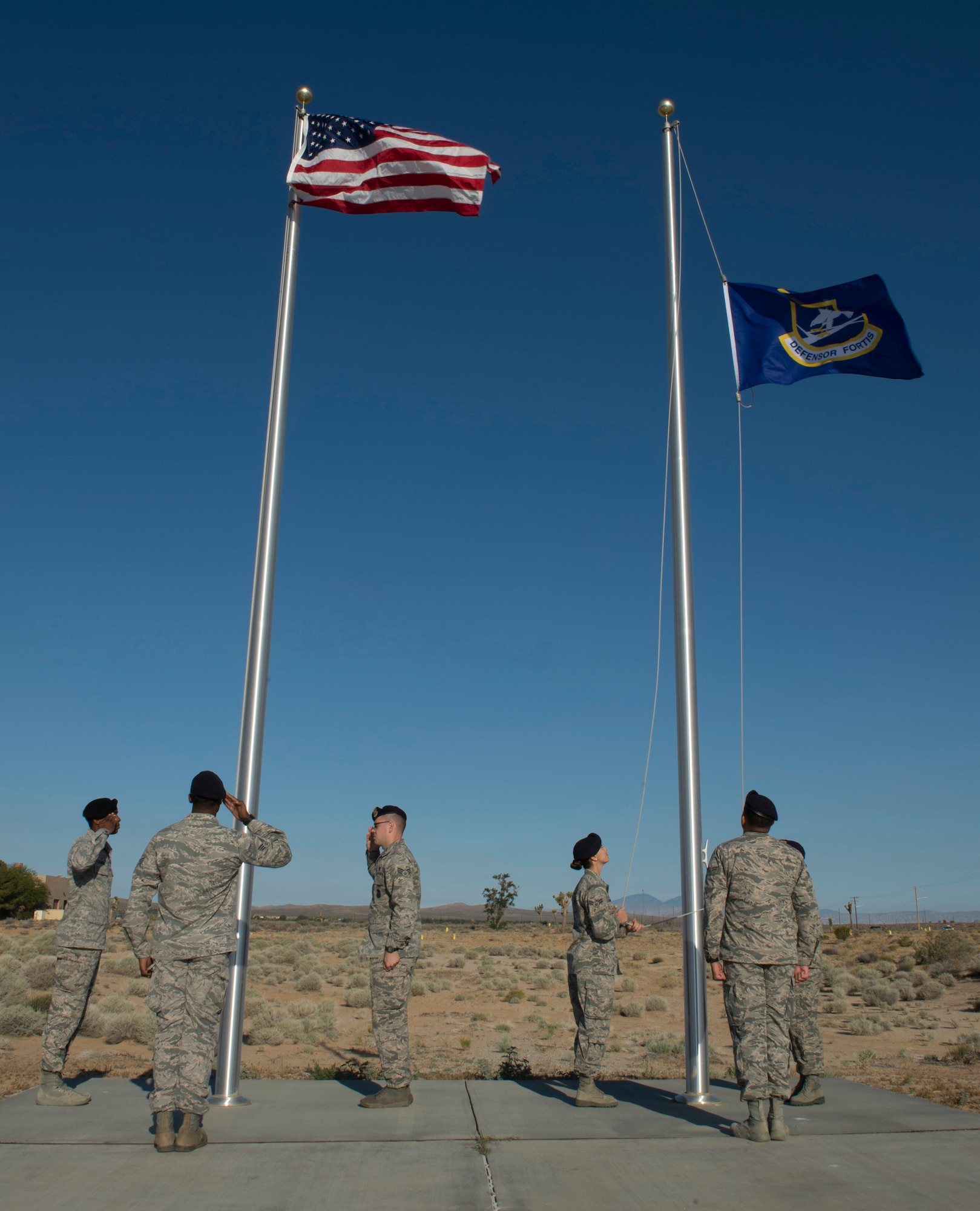 Members of the 412th Security Forces Squadron raise the flags during a reveille ceremony on the Airman Leadership School drill pad here Monday. The ceremony marked the beginning of Police Week. (U.S. Air Force Photo by Joseph Pol Gocon.)