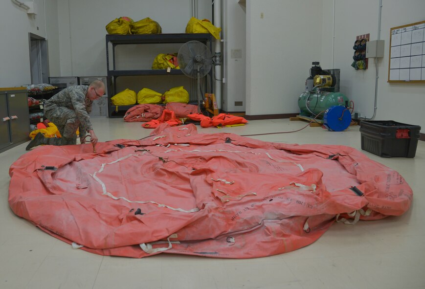 Senior Airman Zachary Cody, 374th Operations Support Squadron aircrew flight equipment journeyman, connects a hose to a life raft to fill it with air at Yokota Air Base, Japan, May 17, 2016. The motor and new air compressor allows the aircrew flight equipment personnel to inflate and inspect life rafts four times faster than before. (U.S. Air Force photo by Senior Airman David Owsianka/Released)