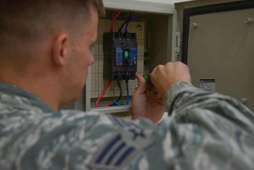Senior Airman Scott Armstrong, 374th Civil Engineer Squadron electrical systems technician, tightens a bolt to connect a wire to the distribution box for a motor to power an air compressor at Yokota Air Base, Japan, May 17, 2016. The CES electrical flight provided 70 feet of raceway pipes, 250 feet of electrical cable, a 20 amp circuit breaker and a 230 volt three-phase industrial motor to power an air compressor to help Aircrew Flight Equipment with the life raft inspection process. (U.S. Air Force photo by Senior Airman David Owsianka/Released)