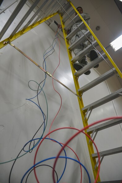 Senior Airman Paul Holmes, 932nd Civil Engineer Squadron electrical systems technician, from Scott Air Force Base, Illinois, prepares to place wires through raceway pipes at Yokota Air Base, Japan, May 17, 2016. The electrical flight provided 70 feet of raceway pipes, 250 feet of electrical cable, a 20 amp circuit breaker and a 230 volt three-phase industrial motor to power an air compressor which helps Aircrew Flight Equipment save time with the life raft inspection process. (U.S. Air Force photo by Senior Airman David Owsianka/Released)