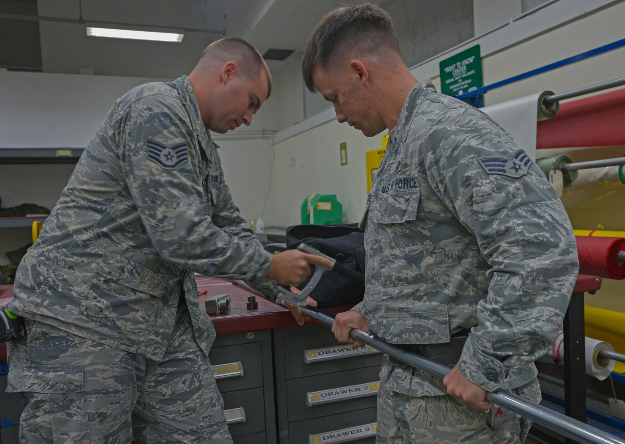 Senior Airman Scott Armstrong, 374th Civil Engineer Squadron electrical systems technician, hold part of a raceway pipe as Staff Sgt. Corey Trowbridge, 932nd Civil Engineer Squadron electrical systems technician, from Scott Air Force Base, Illinois, saws it into two pieces at Yokota Air Base, Japan, May 17, 2016. The electrical flight crew members worked more than 50 man-hours that will save the Aircrew Flight Equipment shop countless hours of life raft inspections helping them turn around the efficiency of being able to produce life saving equipment. (U.S. Air Force photo by Senior Airman David Owsianka/Released)