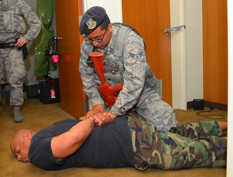 Airman 1st Class John Contreras, 374th Security Forces Squadron patrolman, handcuffs a simulated combatant at Yokota Air Base, Japan, May 13, 2016. Members of the 374 SFS participated in a roleplaying scenario in which they entered a hostile premises and neutralized a simulated active shooter.  (U.S. Air Force photo by Airman 1st Class Elizabeth Baker/Released)