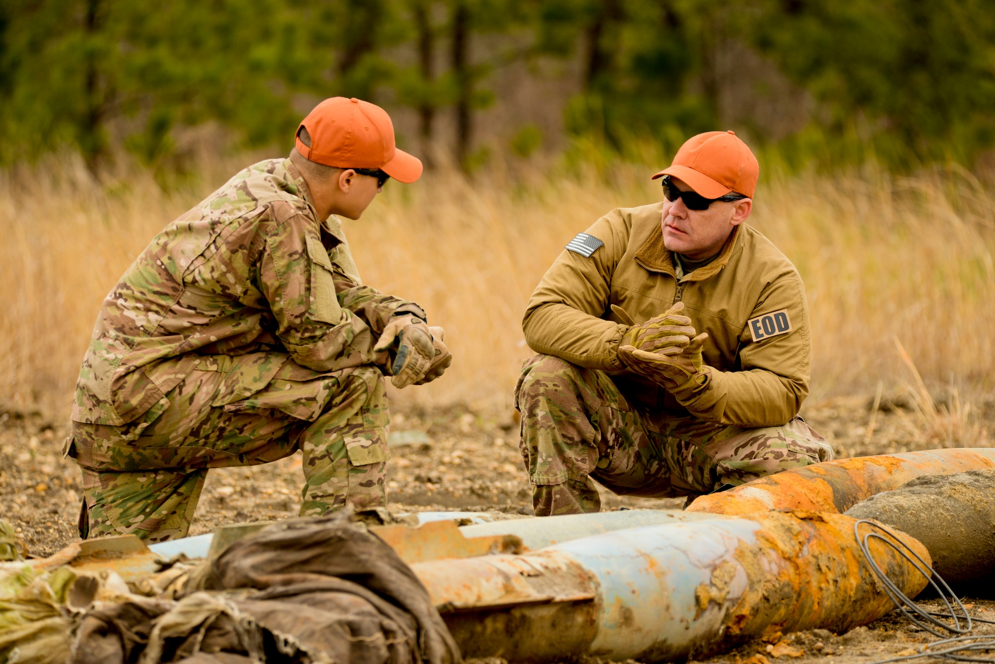 A picture of U.S. Air Force Master Sgt. Raymond Wayne, Explosives Ordnance Disposal (EOD) Technician with the New Jersey Air National Guard's 177th Fighter Wing, and Airman 1st Class Michael Glisan, EOD Tech with the 87th Civil Engineering Squadron, Joint Base McGuire-Dix-Lakehurst, discussing by-the-book techniques for triple stacking C-4 explosives.