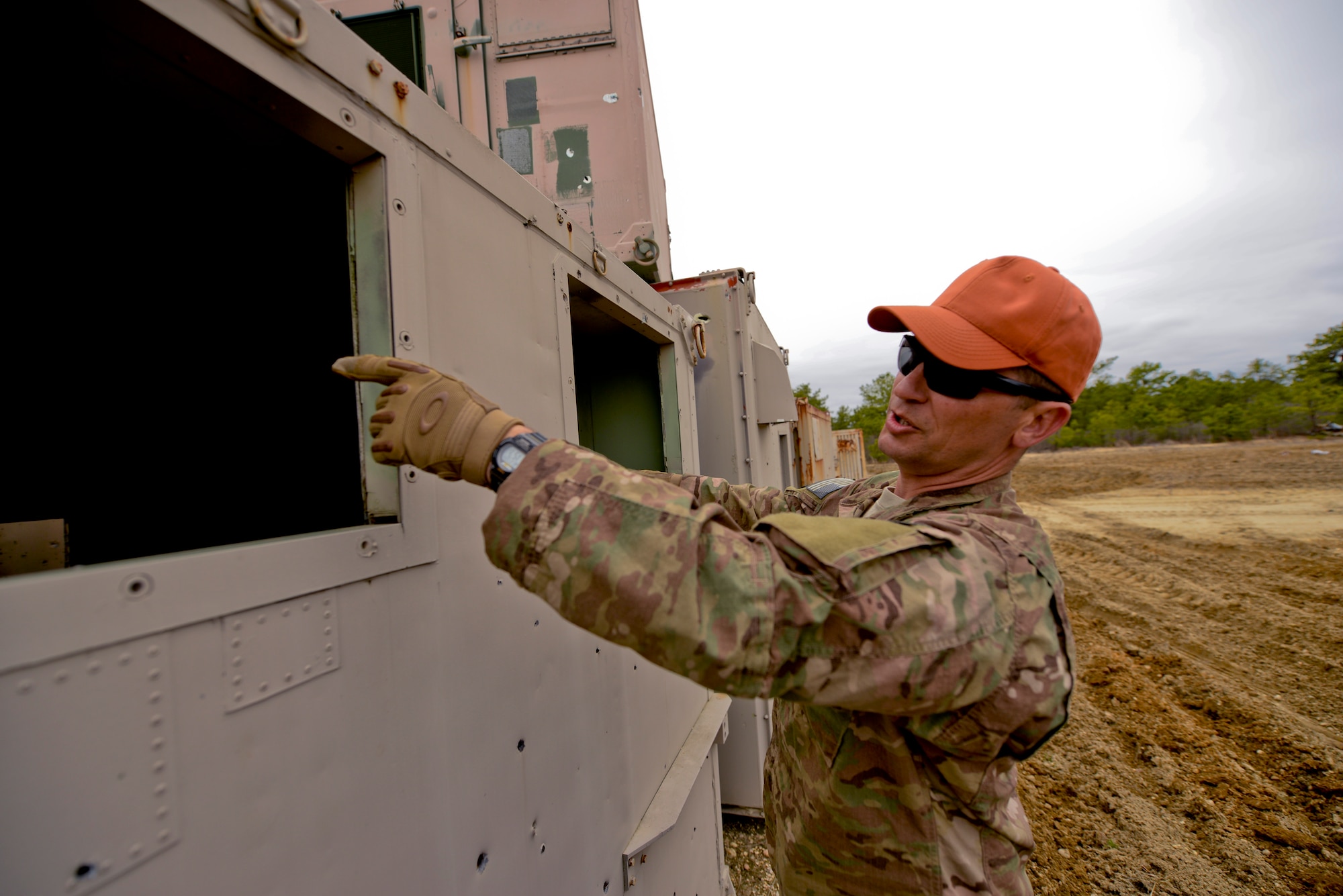 A picture of U.S. Air Force Tech. Sgt. Joseph Coates, Explosives Ordnance Disposal (EOD) technician with the New Jersey Air National Guard, pointing to the entry point of a BDU-33 practice bomb into a simulated village structure.