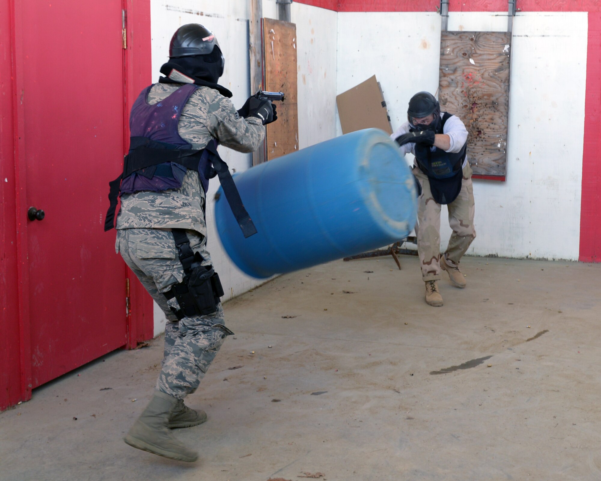U.S. Air Force Tech. Sgt. Thomas J. Moore, 157th Security Forces Squadron flight chief, throws a barrel at Senior Airman Jonathan M. Oconnell, 157 SFS member, during a use of force training scenario at Sig Sauer Academy, Epping, N.H. May 14, 2016. The personal protective equipment they are wearing provides them protection from the non-lethal training ammunition tipped with colored dye which they are using.  (U.S. Air National Guard photo by Airman 1st Class Ashlyn J. Correia)