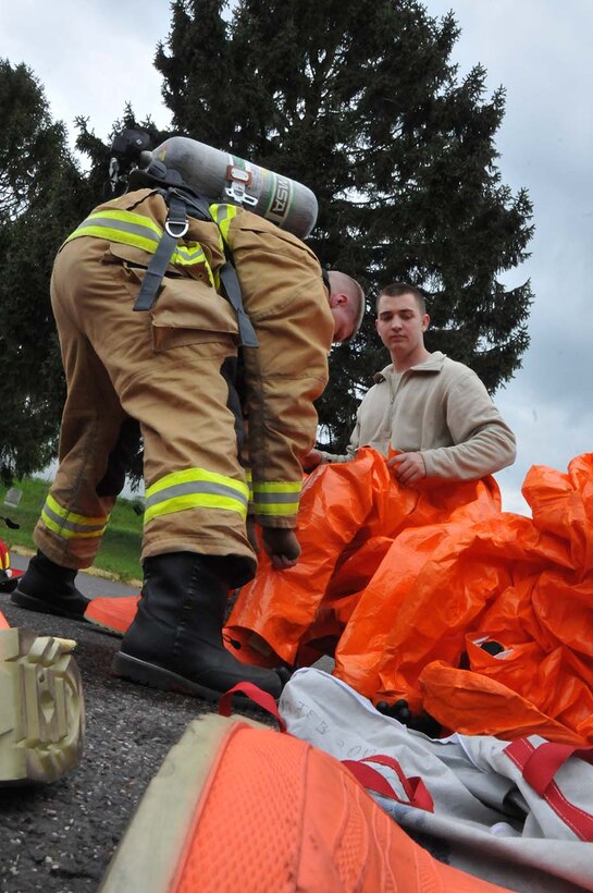 SPANGDAHLEM, Germany -  Tech. Sgt. Karl Reinholz, assists Staff Sgt. Ryan Hart don his HAZMAT gear during a duel-component training mission with their  52nd Fighter Wing, active duty counterparts, May 18, 2016. Reinholz and Hart are among nearly 100 Airmen from the 104th Fighter Wing deployed to Germany for annual training in an effort to support total force integration which combines reservists with active duty Service Members to create one seamless Air Force (U.S. Air National Guard photo by Senior Airman Loni Kingston/Released)