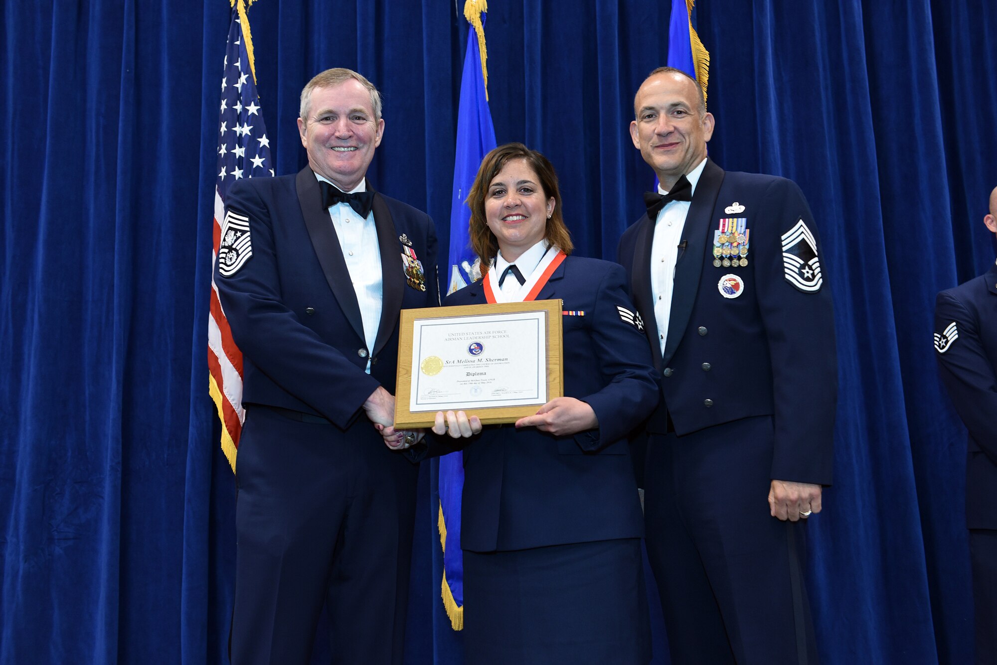 MCGHEE TYSON AIR NATIONAL GUARD BASE, Tenn. - Senior Airman Melissa Sherman, center, takes her diploma here May 18, 2016, as a distinguished graduate of the Airman leadership school, class 16-5, during the graduation banquet at the Chief Master Sgt. Paul H. Lankford Enlisted Professional Military Education Center. (U.S. Air National Guard photo by Master Sgt. Mike R. Smith/Released)