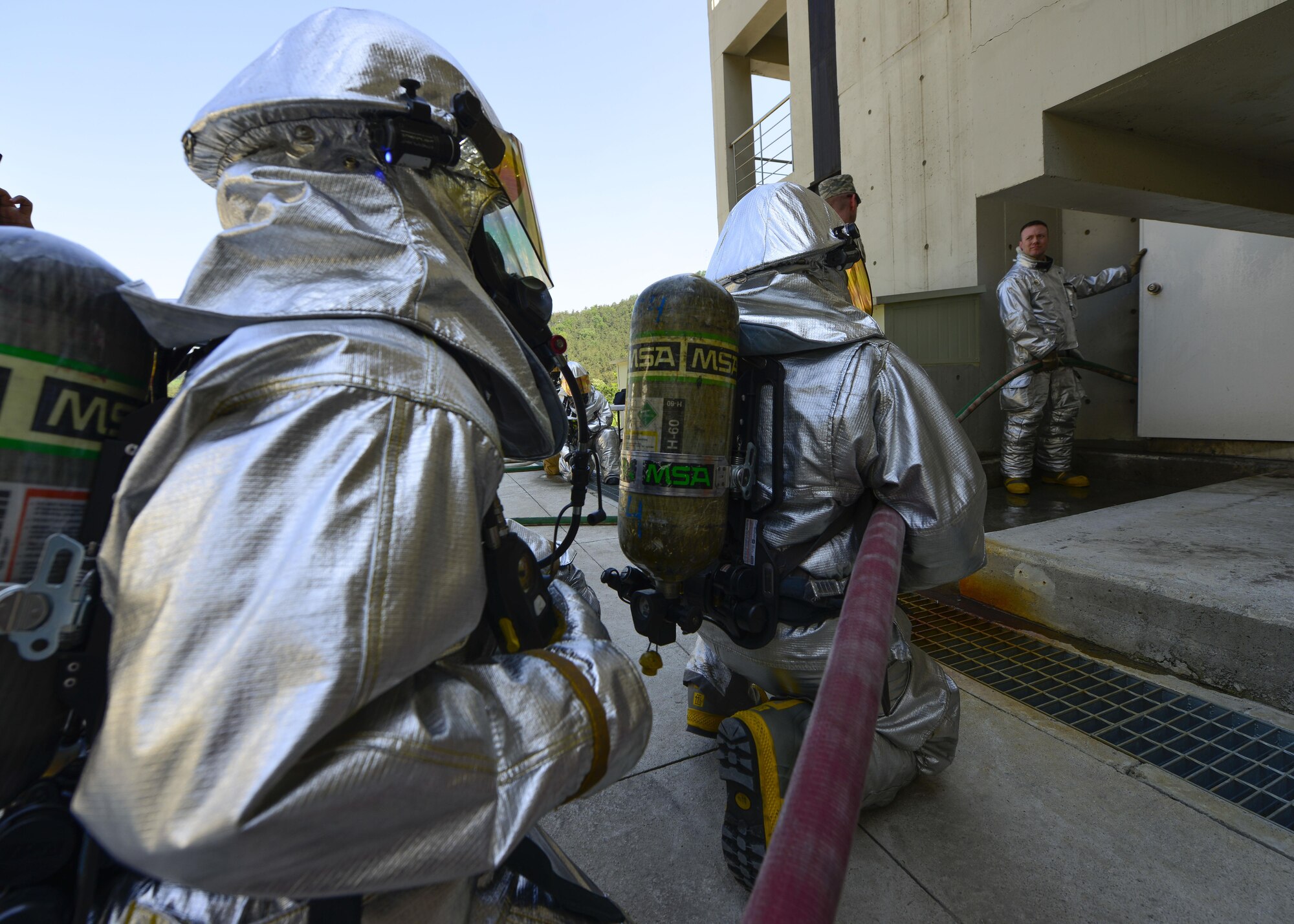 Firefighters from the 51st Civil Engineer Squadron fire and emergency services flight wait for permission to enter a controlled live-fire complex at the Kyonggi-do Fire Academy, Republic of Korea, May 18, 2016. Osan fire and emergency service members regularly train with their Korean counterparts monthly, but this was the first time they conducted an off-base, live fire training scenario. (U.S. Air Force photo by Senior Airman Victor J. Caputo/Released)