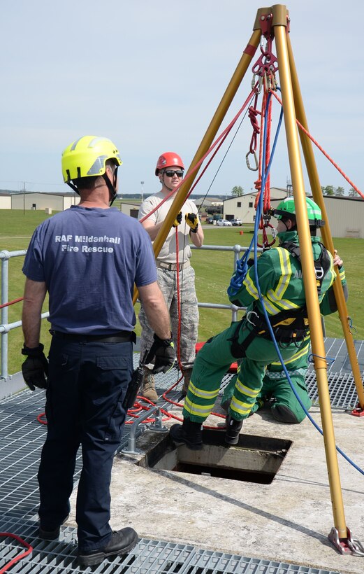 Crew Manager Andrew Hughes, left, 100th Civil Engineer Squadron firefighter; observes U.S. Air Force Senior Airman Conor Delaney, center, 100th CES driver and operator, lowering East of England Ambulance Service Hazardous Area Response Team members into the confined-space entry trainer May 6, 2016, on RAF Mildenhall, England. The team went into the space to assess the ‘victim’ then sent backup and equipment in to ‘rescue’ them. (U.S. Air Force photo by Gina Randall/Released) 