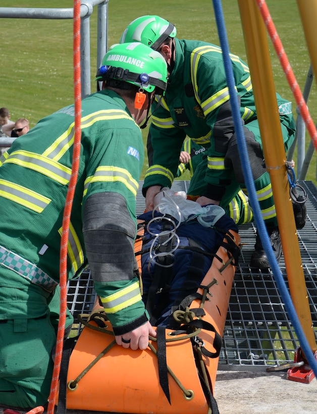 Members of East of England Ambulance Service Hazardous Area Response Team remove a simulated spinal injury victim from a confined space and provide emergency medical care May 6, 2016, on RAF Mildenhall, England. Members of the 100th Civil Engineer Squadron Fire Department teamed up with host nation emergency service responders to share skills and knowledge. (U.S. Air Force photo by Gina Randall/Released)