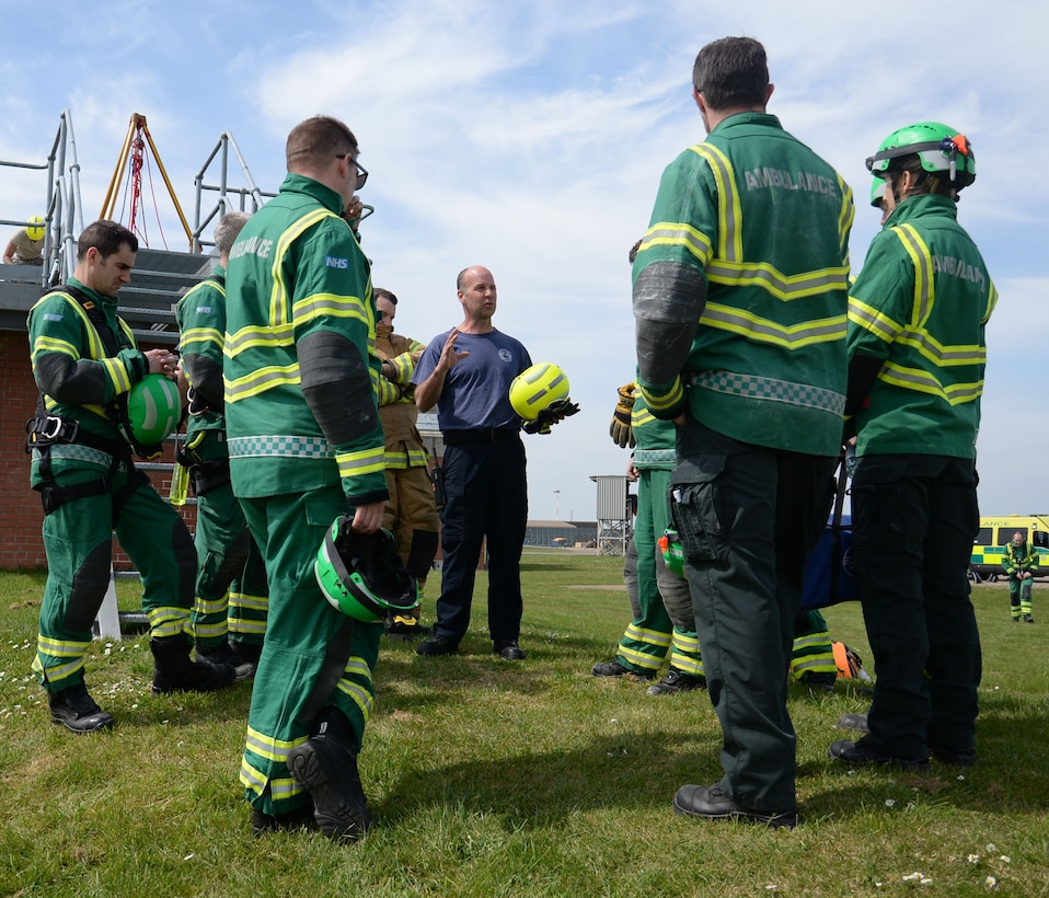 Crew Manager Andrew Hughes, center, 100th Civil Engineer Squadron firefighter, conducts a post operation debrief May 6, 2016, on RAF Mildenhall, England. East of England Ambulance Service Hazardous Area Response Team crews conducted a simulated casualty rescue from a confined space. (U.S. Air Force photo by Gina Randall/Released)