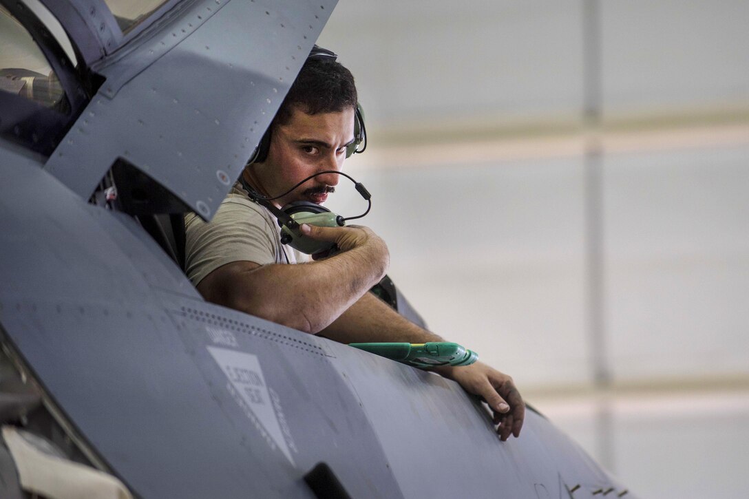Air Force Staff Sgt. Noel Feliciano communicates with fellow airman while working on an F-16C Fighting Falcon aircraft during routine phase maintenance at Bagram Airfield, Afghanistan, May 18, 2016. Feliciano is a phase technician assigned to the 455th Expeditionary Aircraft Maintenance Squadron. Air Force photo by Senior Airman Justyn M. Freeman