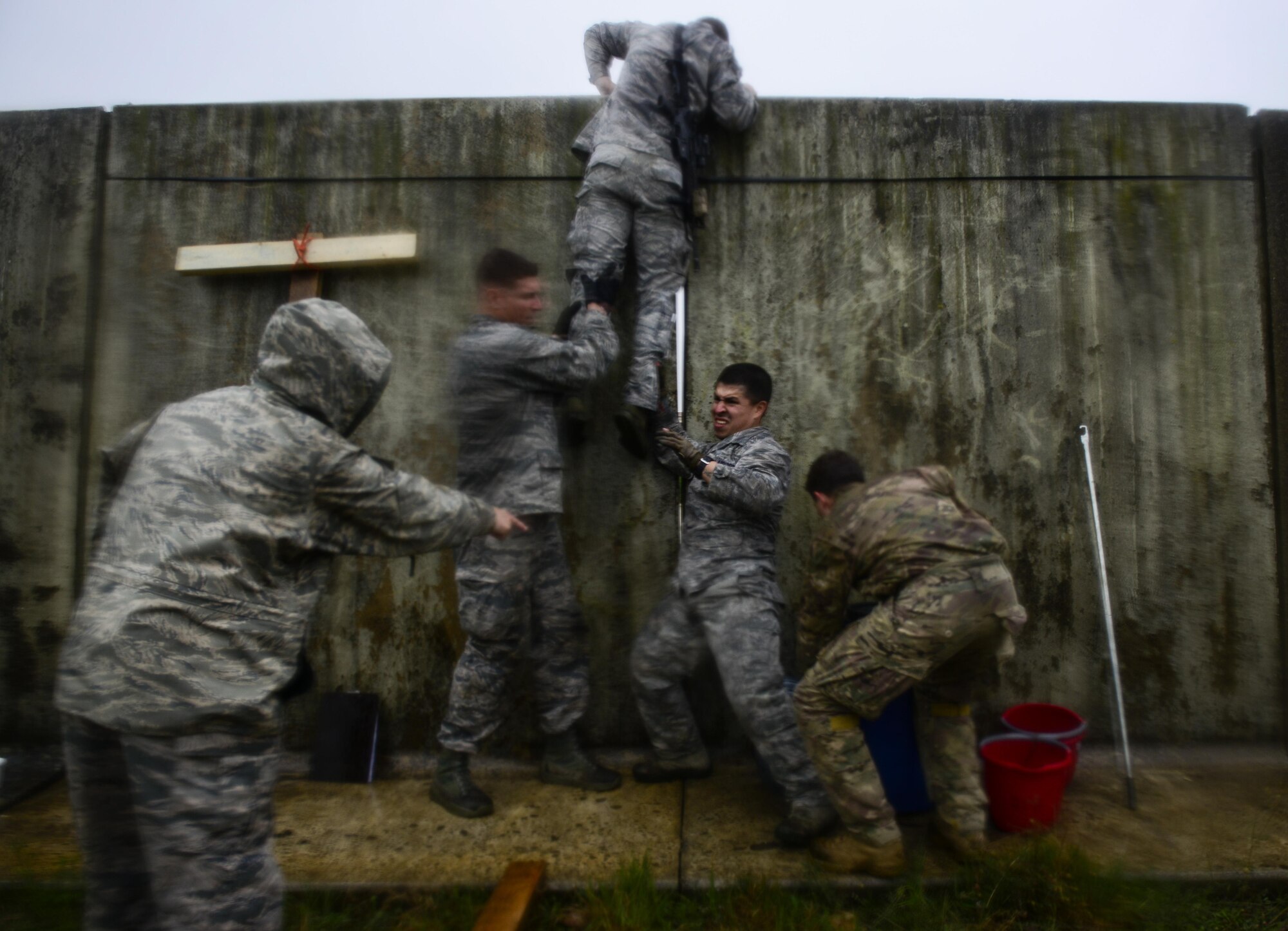 Airmen from the 31st Security Forces Squadron and the 31st Civil Engineering Squadron participate in an event during the Police Week Fire Team Challenge, May 19, 2016, at Aviano Air Base, Italy. Teams had 20 minutes to transport themselves and various items over the wall using limited supplies and without letting them touch the wall. (U.S. Air Force photo by Senior Airman Krystal Ardrey/Released)