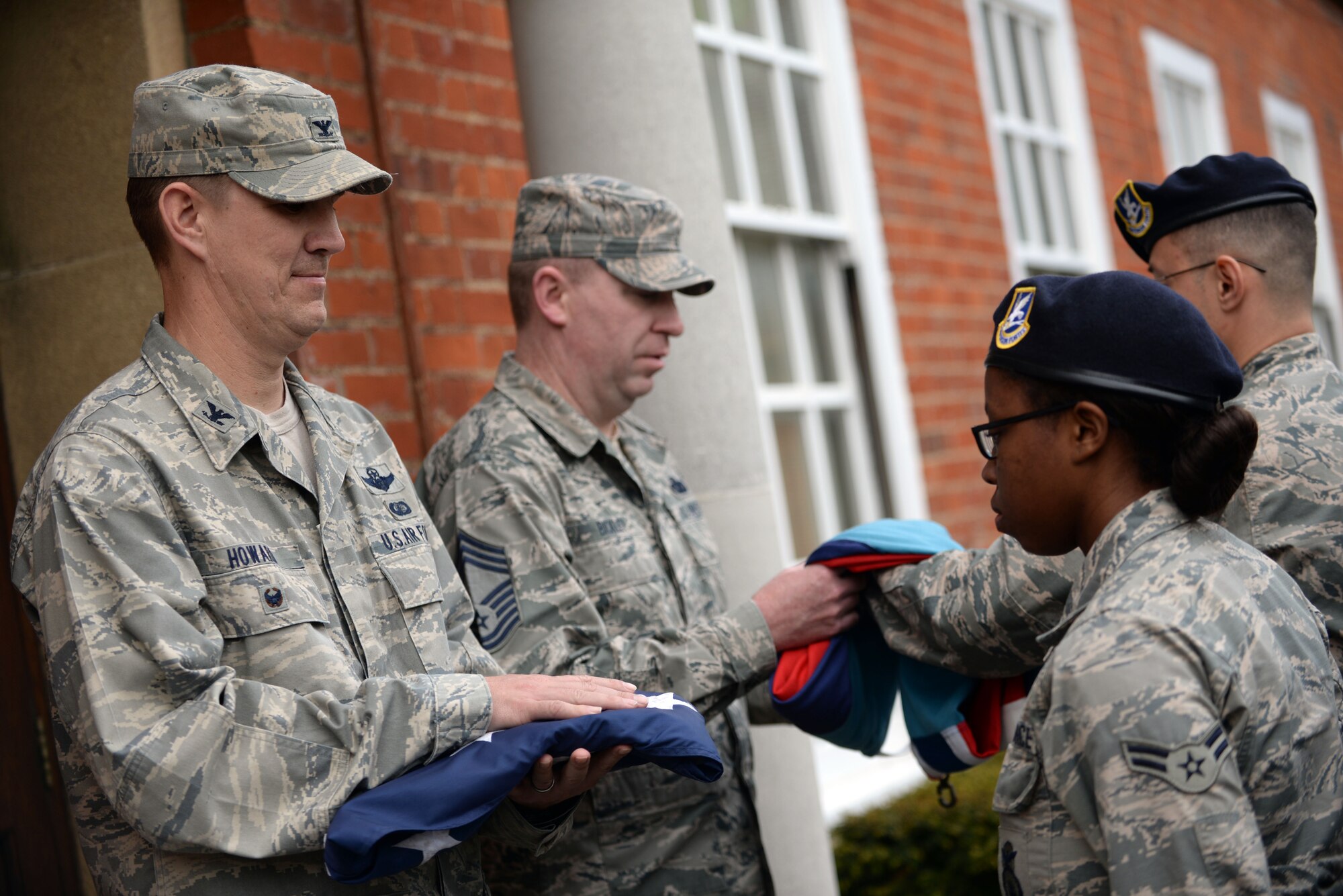 U.S. Air Force Col. John Howard, left, 100th Air Refueling Wing vice commander, and U.S. Air Force Chief Master Sgt. Chad Bickley, center, 100th Mission Support Group command chief, acquire the Royal Air Force ensign and American flag during a retreat ceremony May 19, 2016, on RAF Mildenhall, England. The retreat ceremony was in honor of police officers who have fallen in the line of duty. This event was one of many that the 100th Security Force Squadron hosted as part of National Police Week. (U.S. Air Force photo by Senior Airman Christine Halan/Released) 