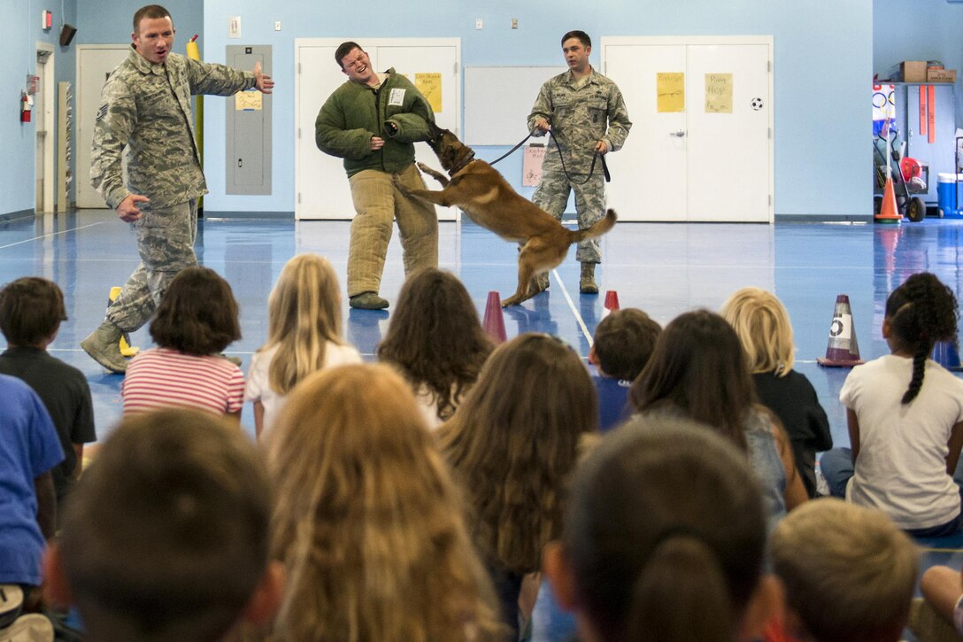 Airmen conduct a military working dog demonstration for Eglin Elementary School students at Eglin Air Force Base, Fla., May 17, 2016. The airmen are assigned to the 96th Security Forces Squadron. More than 100 children watched two military working dog teams perform during the event, which commemorated National Police Week. Air Force photo by Samuel King Jr.